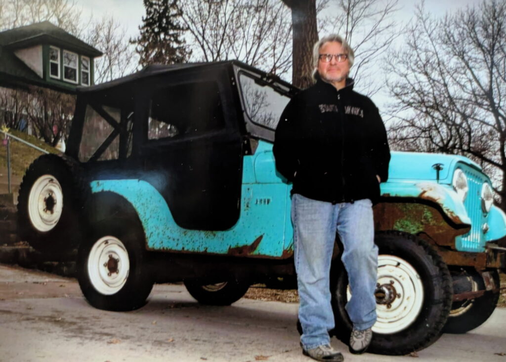 Man stands in front of bright turquoise jeep